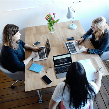 Women sitting around desk with laptops