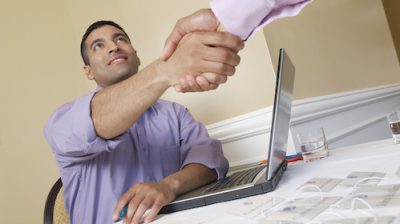 Two men shaking hands over desk with name tags